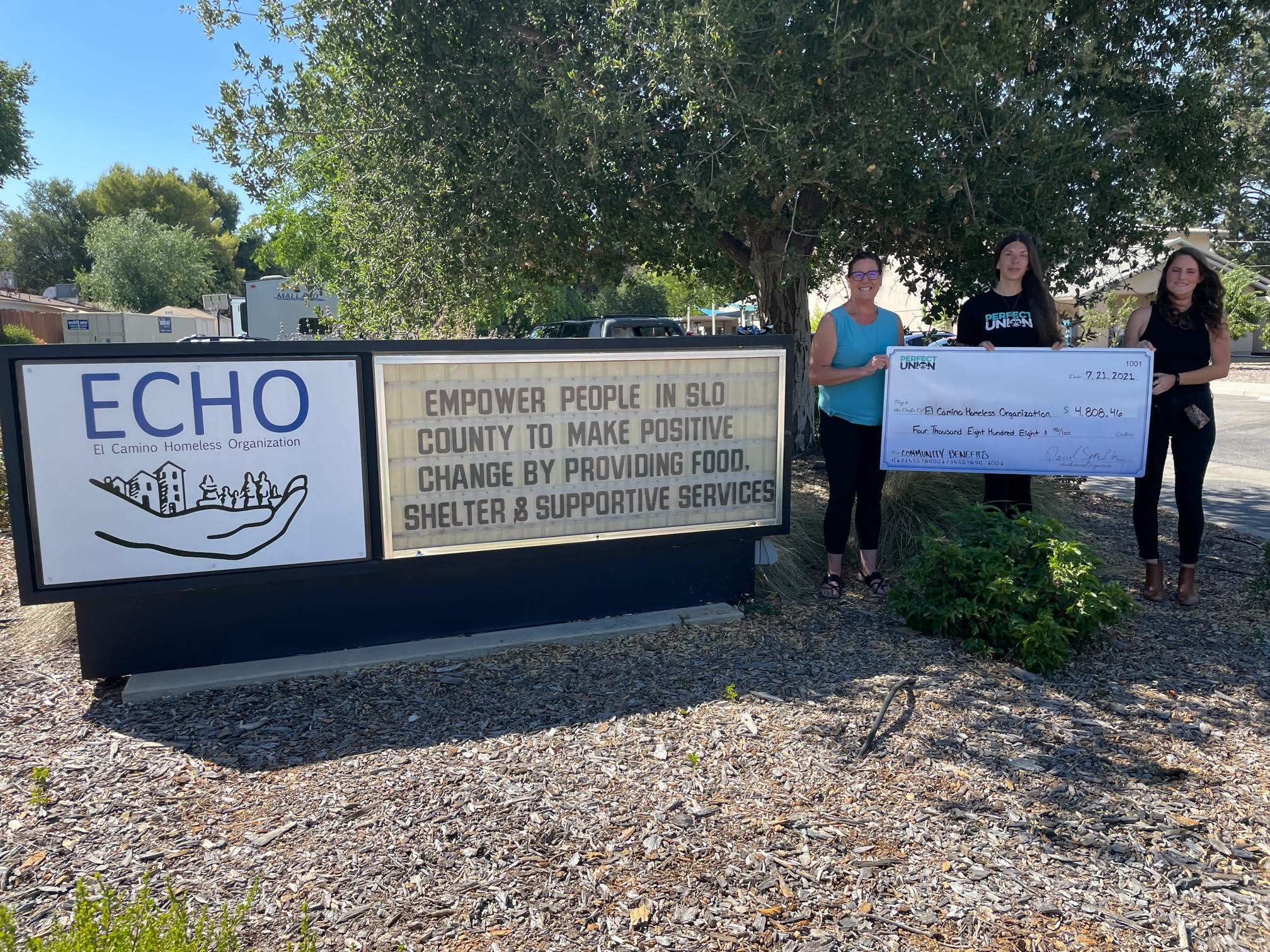 People hold a giant check in from of the ECHO sign